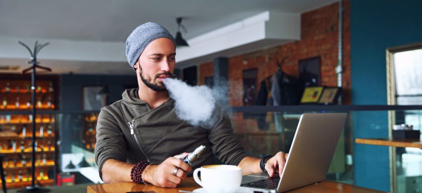 man vaping with laptop